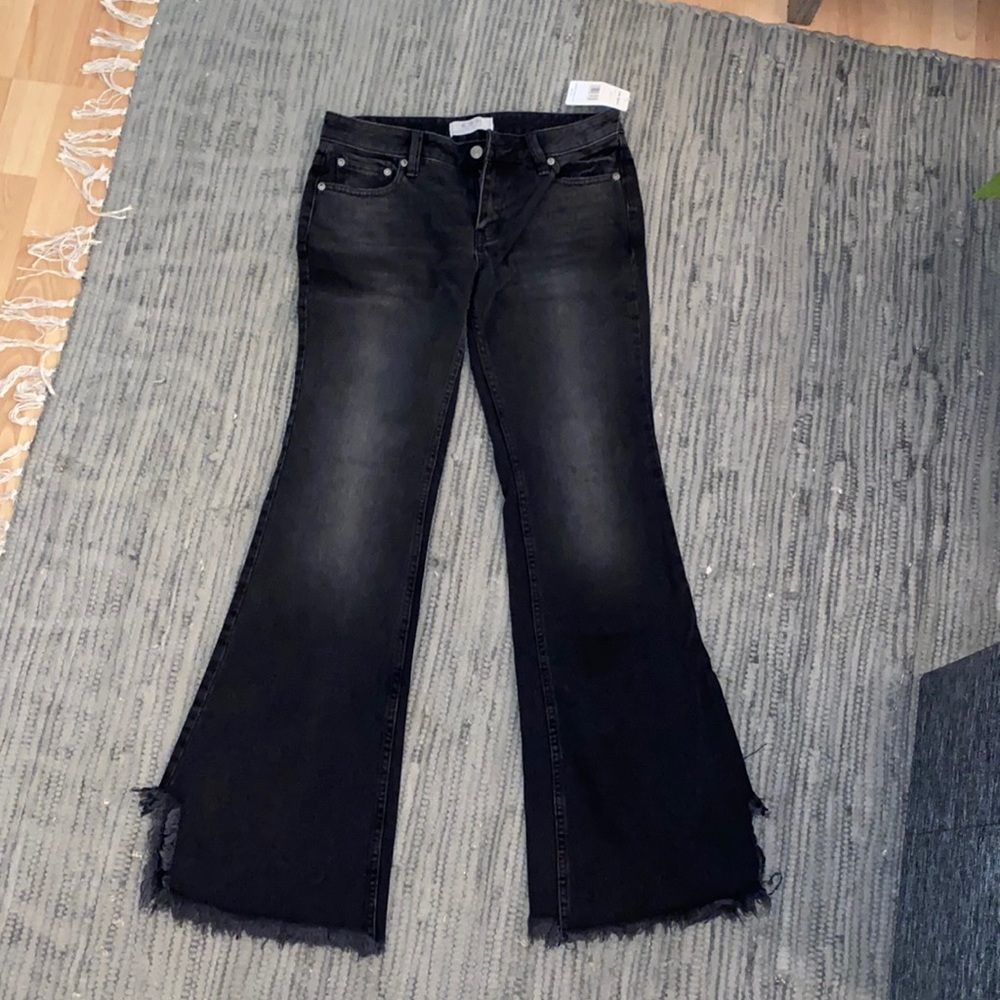 Free People faded black flare jeans with distressed bottoms.